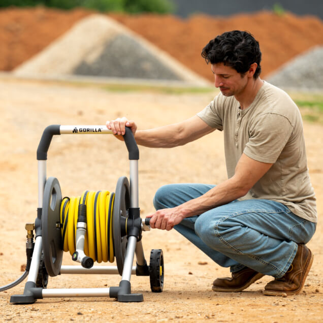 Person using a Gorilla hose reel with a Gorilla garden hose outdoors.