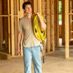 Person carrying a Gorilla hose inside a construction site.