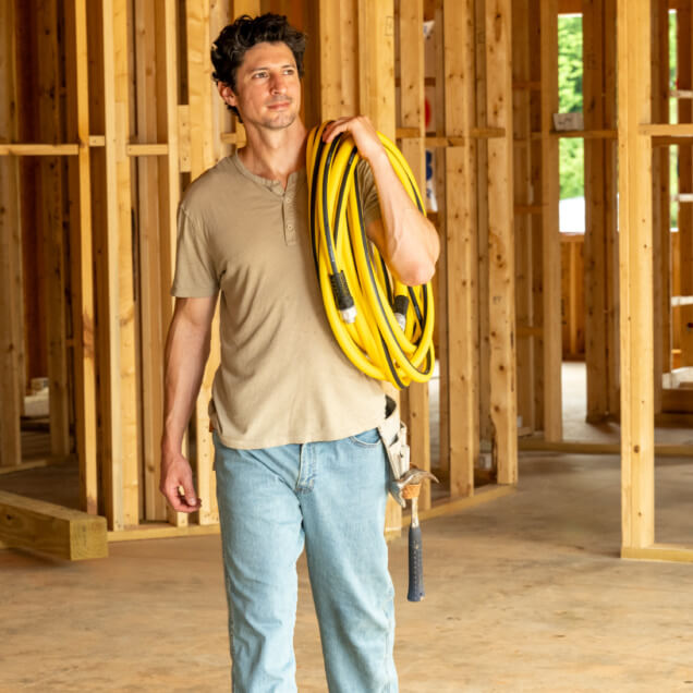 Person carrying a Gorilla hose inside a construction site.